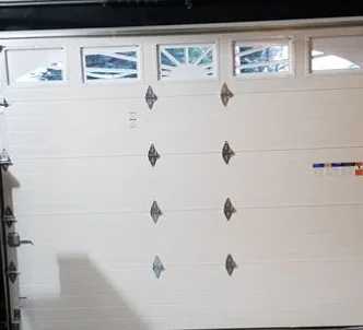 Inside view of a white garage door with a row of sunburst-pattern windows along the top.