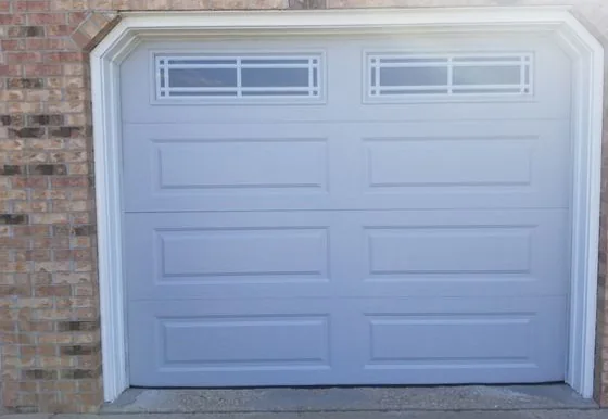 The same opening fitted with a door that has long raised panels and two grid-pattern windows along the top.